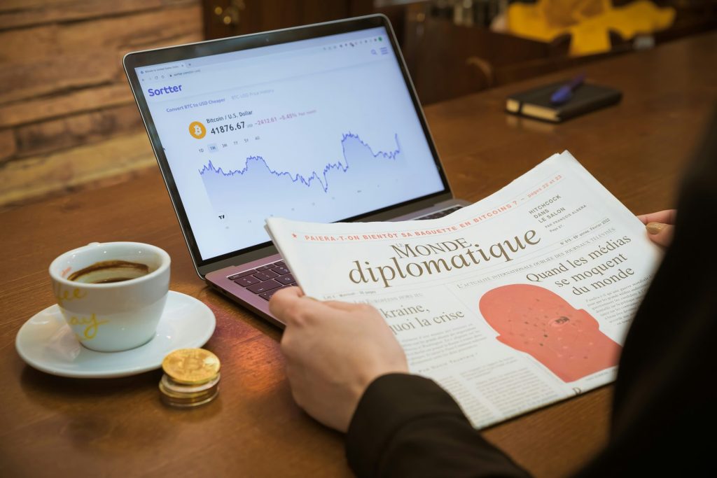 eine Person, die mit einem Laptop und einer Tasse Kaffee an einem Tisch sitzt