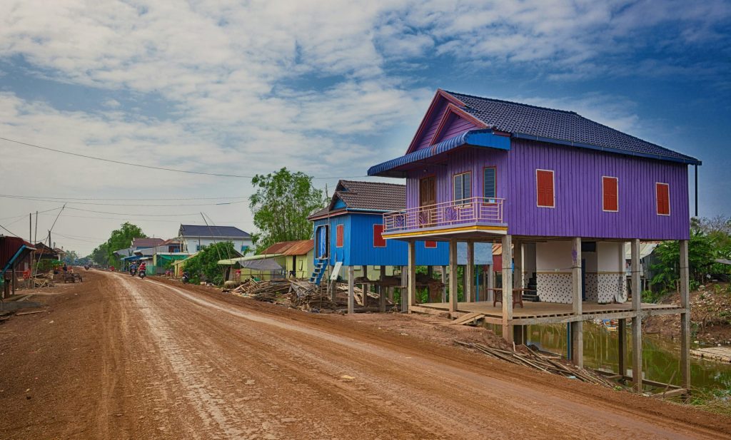 blaues und rosa Holzhaus in der Nähe der Straße unter blauem Himmel tagsüber